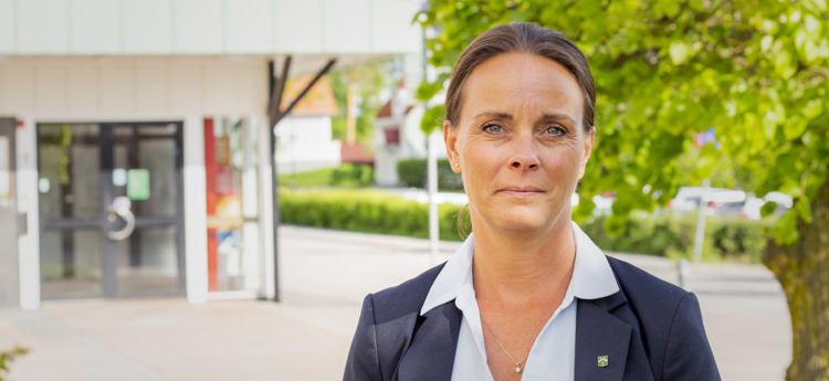 Kommundirektör Linda Ljungqvist står framför entrén till kommunhuset i Åtvidaberg.