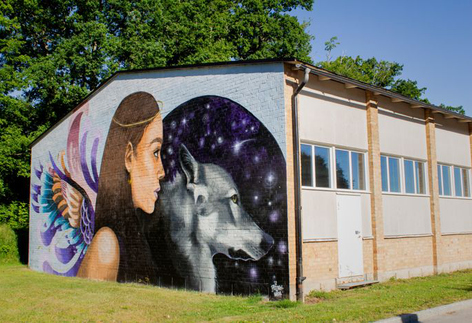 Långbrottshallens vägg täckt av en stor väggmålning föreställande en flicka och en varg. 