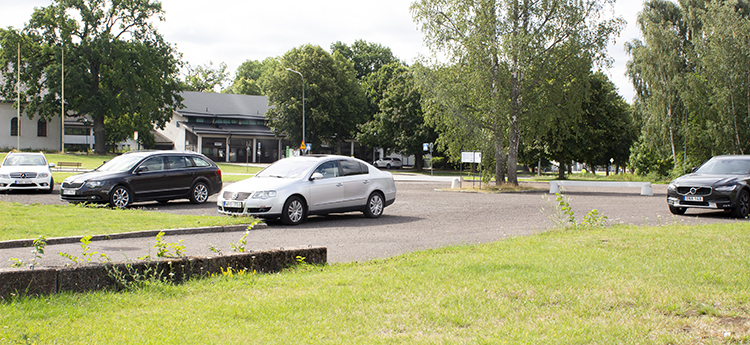 Fyra bilar i olika modeller och färger står parkerade på parkeringen Ålundaplan.